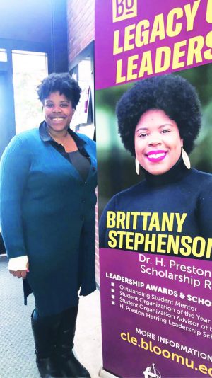 Senior Brittany Stephenson, the recipient of the Dr. H. Preston Herring Scholarship, stands with the poster promoting her achievement in Bakeless. 