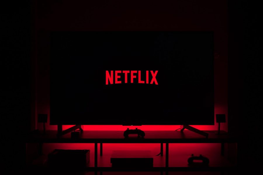 A+dark+screen+shows+the+red+Netflix+logo.+The+background+of+the+screen+is+illuminated+by+a+red+LED+light.