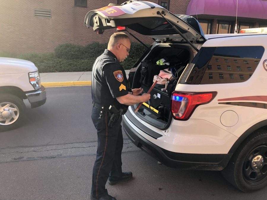 Sgt. Andrew Hirko grabs roadflares to dispense at the scene of a broken down car outside of Elwell Hall