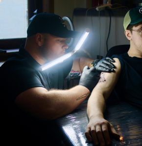 An artist of Tucci's Tattoo Parlor, Cory Radkins, tattooing a client. 