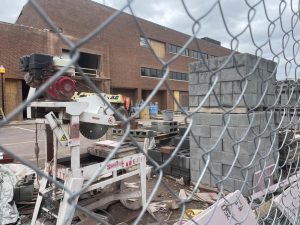 Passersby are subjected to peering through a fence towards the ongoing construction. 